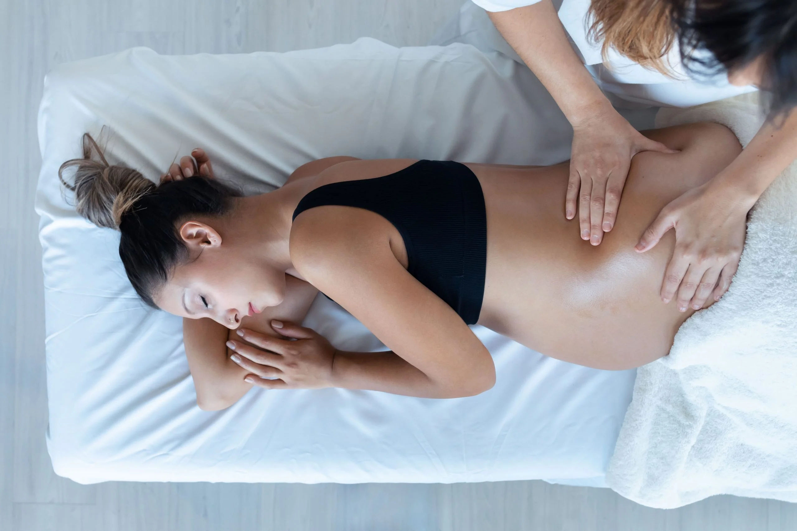 Pregnant woman receiving a gentle pregnancy massage while lying on her side for comfort and relaxation