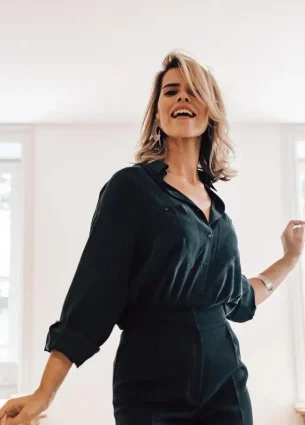 Smiling woman in an office setting, representing the positive energy and reduced stress achieved through regular chair massages.