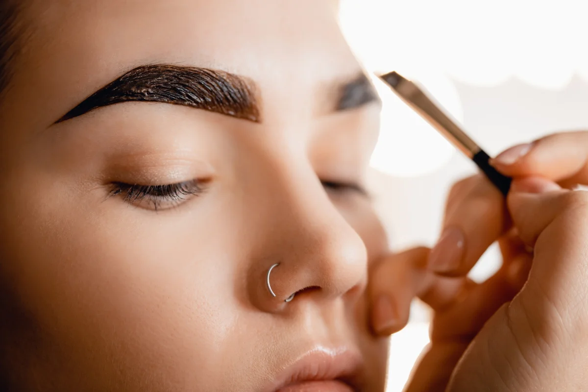 Beautician applying light tint to enhance natural, lighter-colored brows.