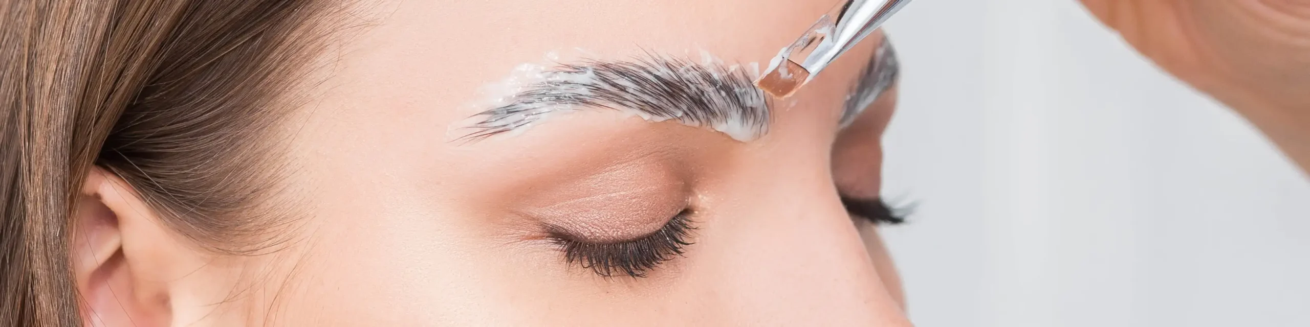 Eyebrow lamination procedure in Dubai with a technician applying lifting solution for fuller, well-shaped brows