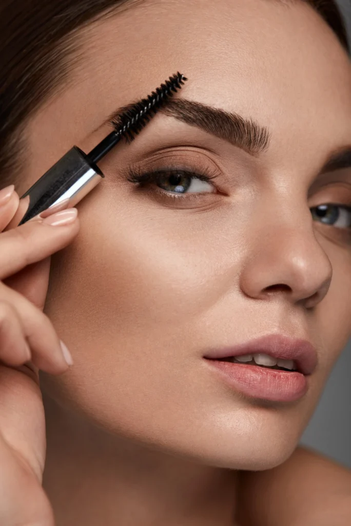 Woman applying HD Brows treatment with brush for perfectly shaped eyebrows.