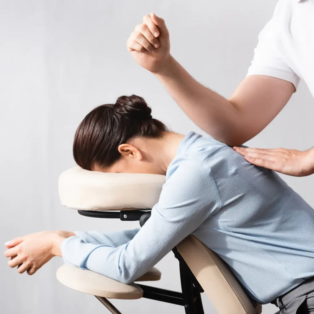 Professional corporate wellness session with a therapist providing a relaxing chair massage to a woman in a workplace setting.