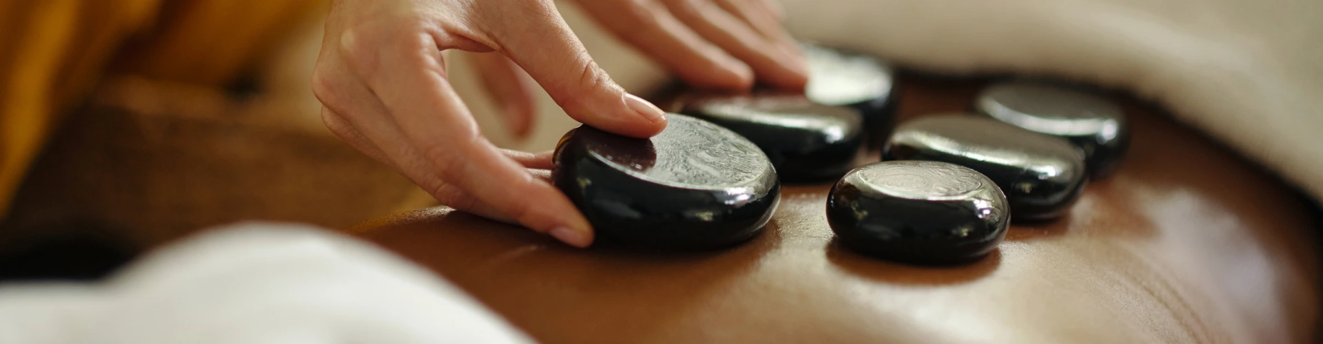 Heated basalt stones arranged along the spine during a hot stone massage session at home in Dubai