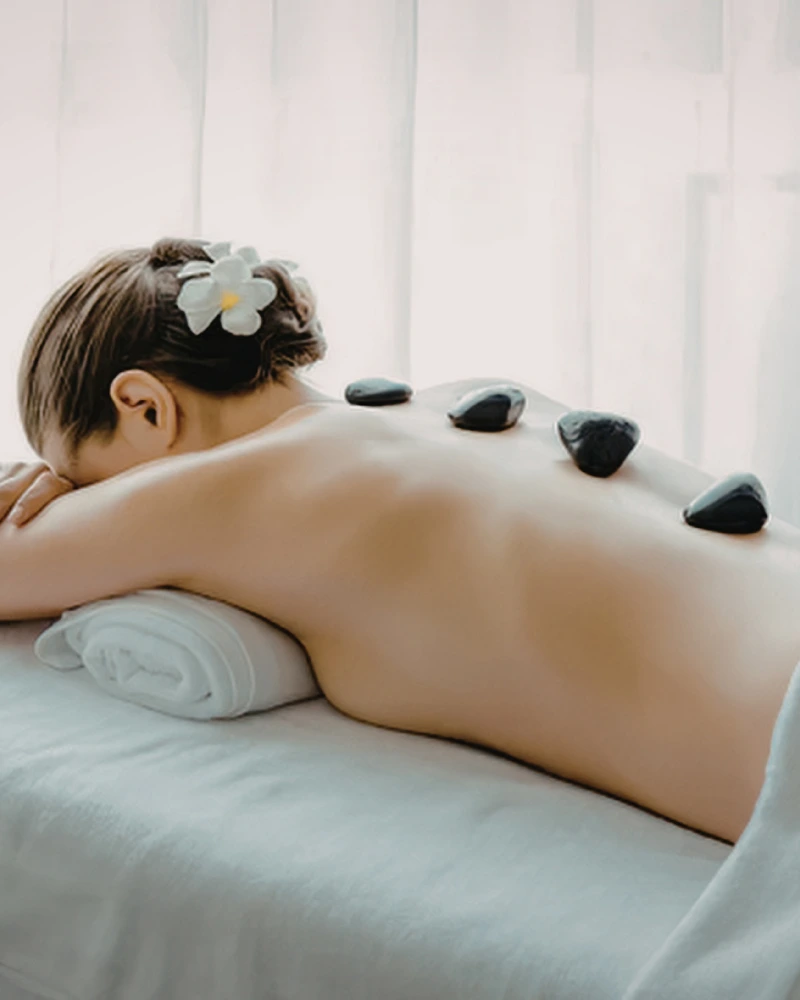 Hot stone massage with heated basalt stones placed along the spine during a home session in Dubai